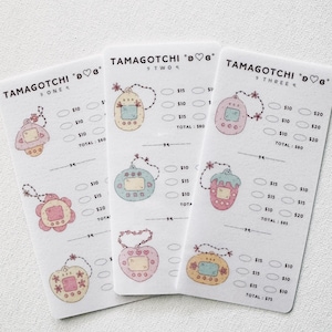 Op de afbeelding: Drie witte kaarten met pastelkleurige Tamagotchi-ontwerpen en de tekst "TAMAGOTCHI" bovenaan. Elke kaart heeft verschillende Tamagotchi-illustraties, prijscirkels en totalen. De kaarten liggen op een witte ondergrond.