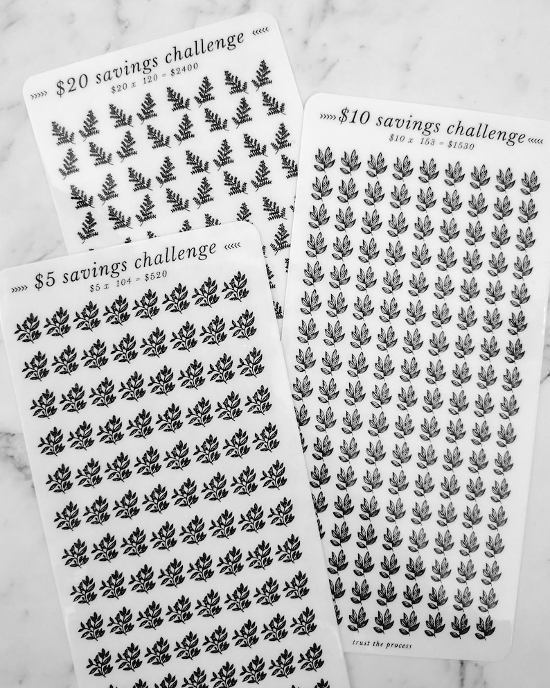 May include: Three sheets of stickers with black leaf designs. The sheets are labelled with the text "$20 savings challenge", "$10 savings challenge", and "$5 savings challenge". Each sheet has a different number of stickers.
