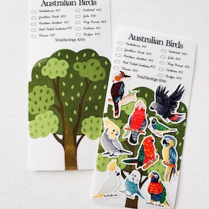 Pode incluir: Dois cartões brancos com o texto "Australian Birds" e uma lista de nomes de pássaros e preços. Um cartão apresenta uma ilustração de árvore, o outro tem adesivos de pássaros coloridos, incluindo um kookaburra, uma cacatua e um periquito. Economia total $250.