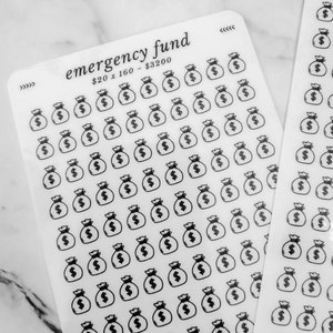 May include: A sheet of clear stickers with black money bag icons. The sheet has the text "emergency fund £20 x 160 - £3200" printed on it.