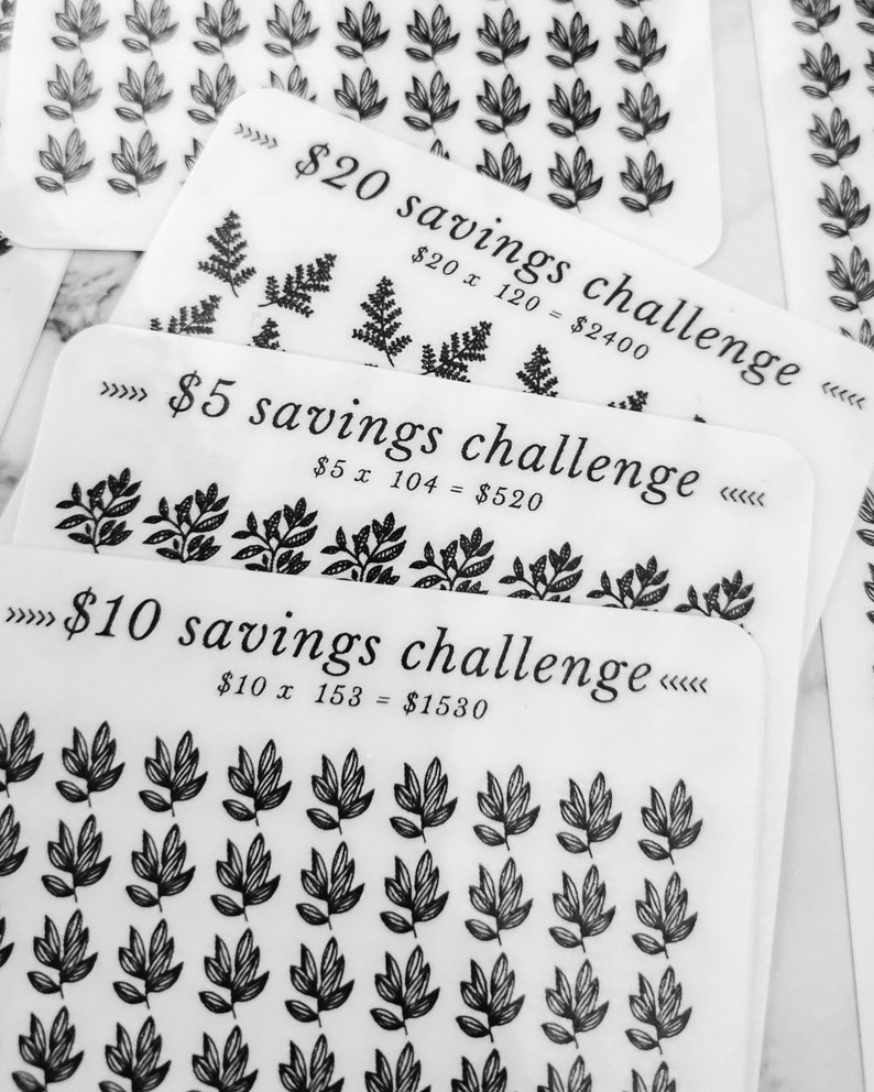 May include: Three white cards with black text and illustrations of leaves. The cards are labelled "&pound;20 savings challenge", "&pound;5 savings challenge", and "&pound;10 savings challenge". Each card has a math equation showing the total savings for each challenge.