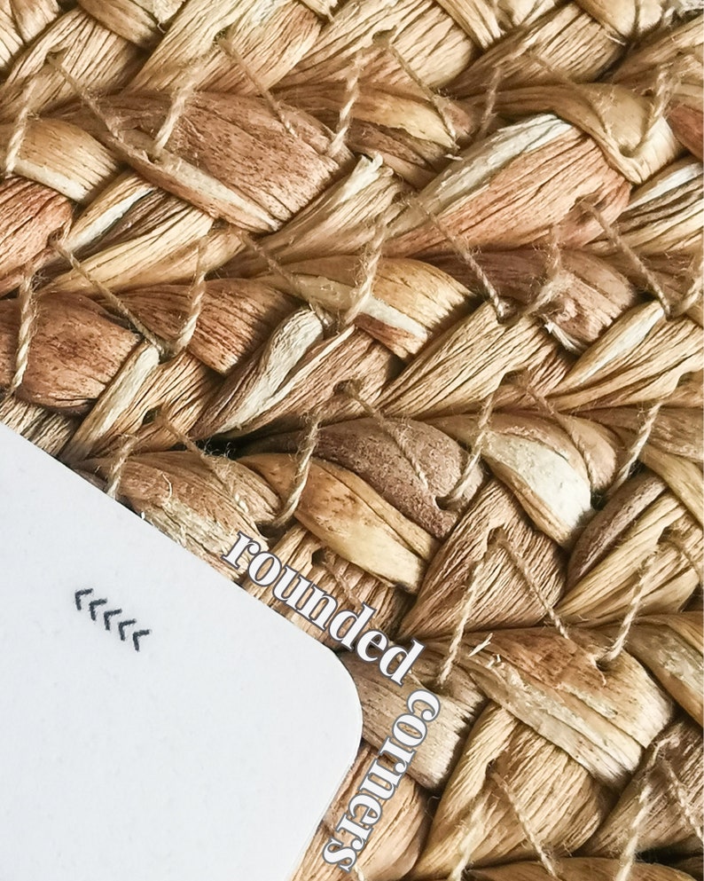 May include: A white card with rounded corners and the text "rounded corners" written on it. The card is lying on a woven, light brown, natural fiber surface.