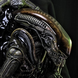 Peut inclure: Sculpture détaillée d'une créature Alien, avec un design biomécanique et une palette de couleurs sombres. La sculpture présente une surface texturée avec des détails complexes, dont une tête en forme de crâne et des membres allongés. Le texte "FINAL PRODUCT" est visible.