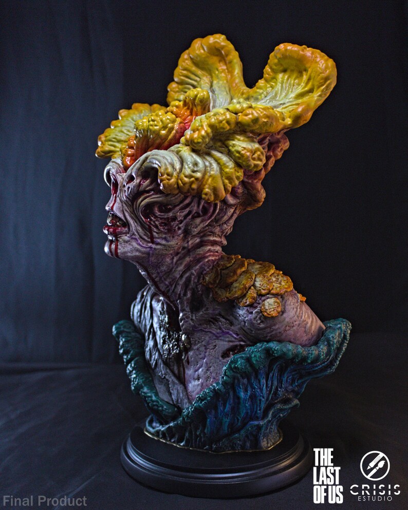 May include: A detailed bust of a Clicker from The Last of Us. The sculpture features a grotesque, mutated human head with fungal growth in shades of yellow, orange, and green. The bust is mounted on a black base, with the game's logo visible.