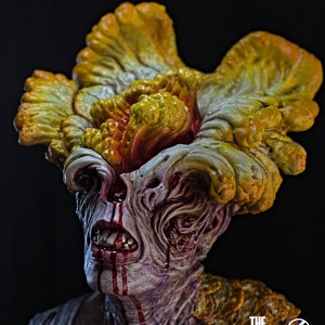 May include: A detailed sculpture of a zombie-like creature from "The Last of Us." The figure has a grotesque appearance with exposed teeth, blood dripping from the mouth and eyes, and a large, mushroom-like growth on its head. The sculpture is set against a dark background.