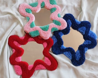 Può includere: Tre specchi a forma di stella con cornici sfocate, colorate e testurizzate. Gli specchi sono rosa, blu e rosso.