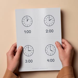 Könnte beinhalten: Eine weiße Karte mit vier Uhren, die jeweils eine andere Uhrzeit anzeigen: 1:00, 2:00, 3:00 und 4:00 Uhr. Die Uhren sind schwarz-weiß, mit deutlich angezeigter Uhrzeit. Die Karte wird von Händen gehalten.