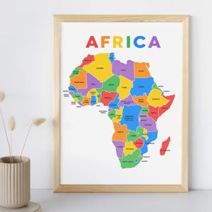 Könnte beinhalten: Eine gerahmte Karte von Afrika mit einer farbenfrohen Illustration des Kontinents, wobei jedes Land durch eine andere Farbe gekennzeichnet ist. Das Wort "AFRIKA" steht in Regenbogenfarben oben. Der Rahmen ist aus hellem Holz.