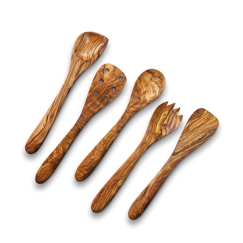 Puede incluir: Conjunto de cinco utensilios de cocina de madera, que incluyen una cuchara ranurada, una cuchara, una cuchara para servir, un tenedor y una esp&aacute;tula. Los utensilios est&aacute;n hechos de madera de olivo y tienen un color marr&oacute;n natural.