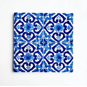 May include: Four blue and white ceramic tiles with a repeating geometric pattern. The tiles are arranged in a square.