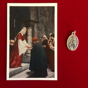 May include: An image of a religious art print and a silver pendant. The print depicts a woman in a red dress distributing bread to people. The pendant features an image of a saint and the words "ST. ELIZABETH OF HUNGARY".