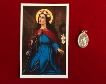 May include: An image of a religious icon and a silver pendant. The icon shows a woman in a blue dress and red cape, holding arrows and flowers. The pendant features a woman's portrait and the inscription "St. Philomena".