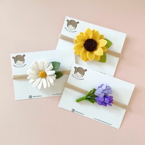 May include: Three felt flower headbands on white cards with the text "felt & luxe" and social media handles. The headbands feature a yellow sunflower, a white daisy, and a purple lavender bouquet.