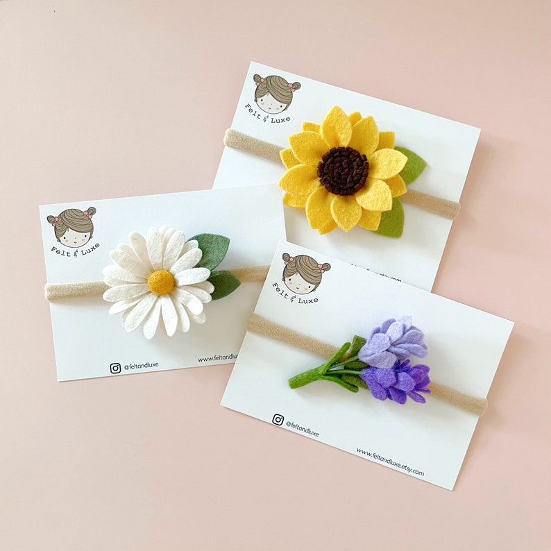 May include: Three felt flower headbands on white cards with the text "felt & luxe" and social media handles. The headbands feature a yellow sunflower, a white daisy, and a purple lavender bouquet.