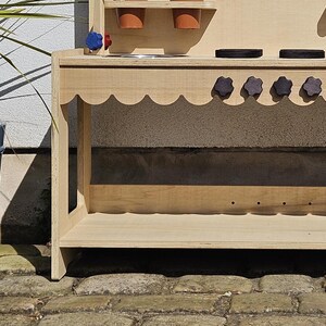 Stylish scalloped mud kitchen with four ring hob, four dials,two stainless steel sinks, two taps with hot and cold handles