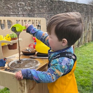 small boy playing mudpies in his mud kitchen sink