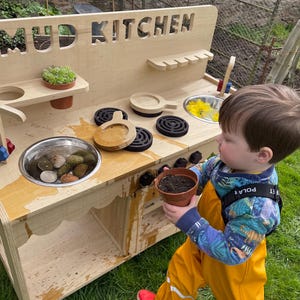 small boy playing with mud in his mud kitchen sink, outdoor play