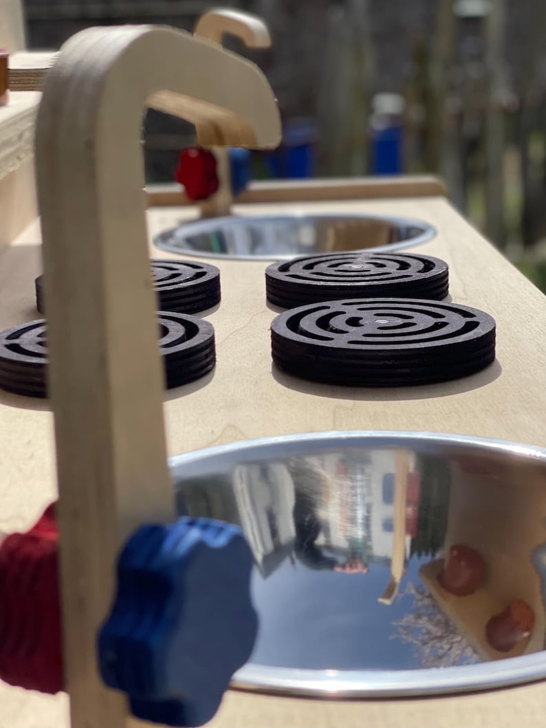 close up of the stainless steel mud kitchen sinks, hob rings and taps