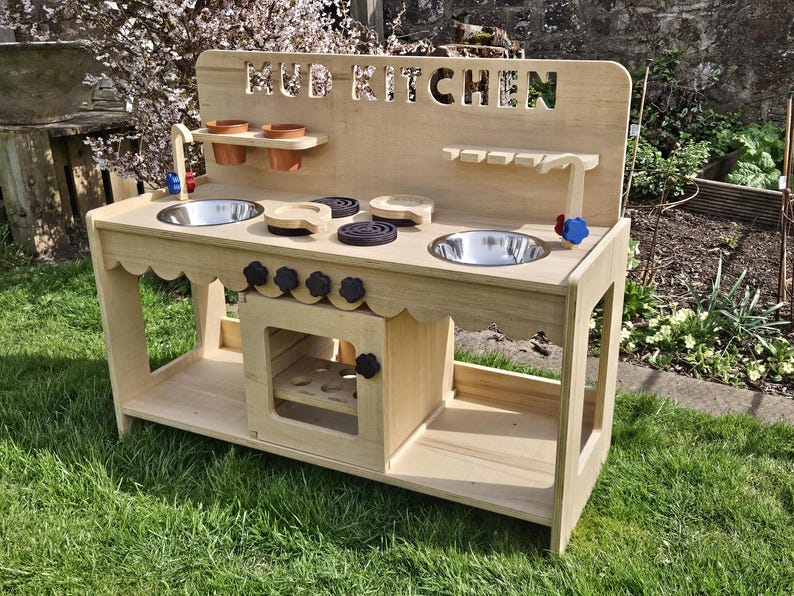 Stylish scalloped mud kitchen with four ring hob, four dials,two stainless steel sinks, two taps with hot and cold handles andwith full oven and shelf