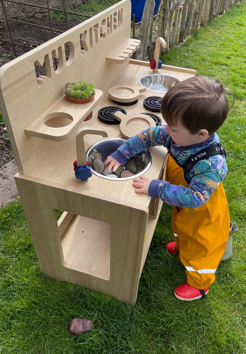 small boy playing with rocks in his mud kitchen sink