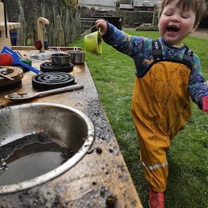 little boy having a lot of fun with muddy kitchen play