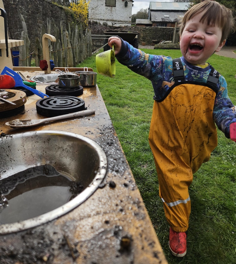 little boy having a lot of fun with muddy kitchen play