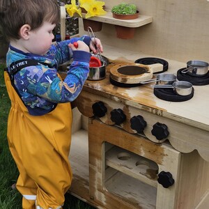 Stylish scalloped mud kitchen with four ring hob, four dials,two stainless steel sinks, two taps with hot and cold handles andwith full oven and shelf