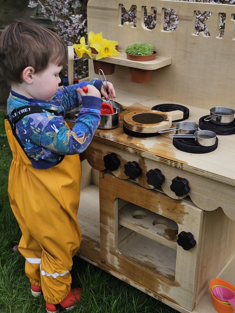 Stylish scalloped mud kitchen with four ring hob, four dials,two stainless steel sinks, two taps with hot and cold handles andwith full oven and shelf