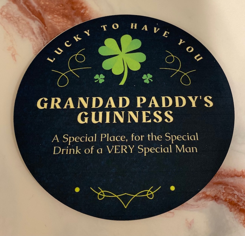 May include: A round, black coaster with a green shamrock and the text "Lucky to have you Grandad Paddy's Guinness A Special Place, for the Special Drink of a VERY Special Man".