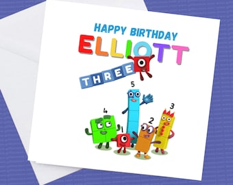 May include: A birthday card featuring the characters from the show "Numberblocks" with the name "ELLIOTT" and the word "THREE" in colorful letters. The card is white with a rainbow background.