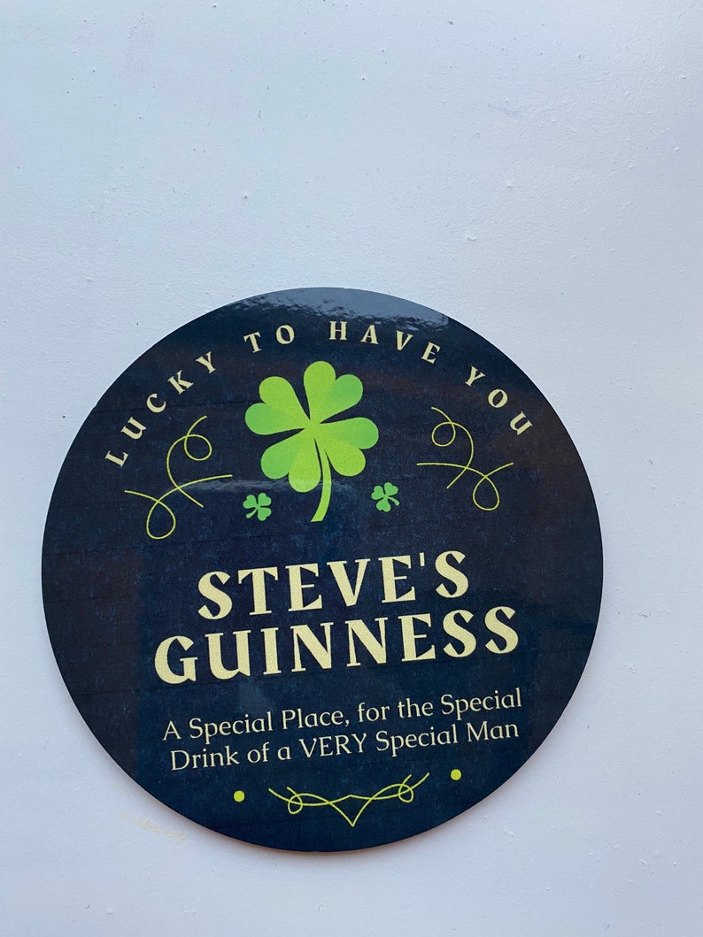 May include: A black and green round sign with the text "LUCKY TO HAVE YOU" and "STEVE'S GUINNESS" in a white font. The sign also includes a green four-leaf clover and the text "A Special Place, for the Special Drink of a VERY Special Man".