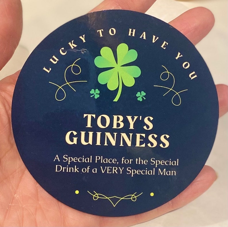 May include: A round, blue and gold sticker with a four-leaf clover and the text "LUCKY TO HAVE YOU". Below the clover is the text "TOBY'S GUINNESS" and "A Special Place, for the Special Drink of a VERY Special Man".