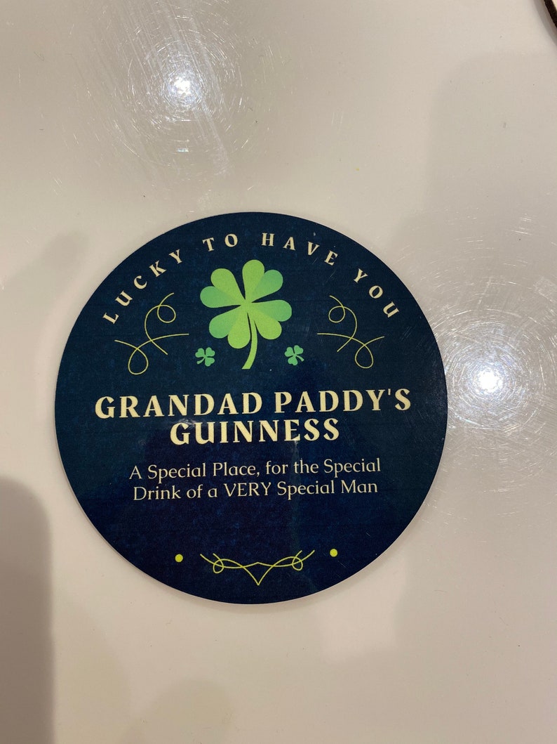 May include: A round, blue and green coaster with the text "Lucky to have you" and "Grandad Paddy's Guinness" with a shamrock design. The text below reads "A Special Place, for the Special Drink of a VERY Special Man."