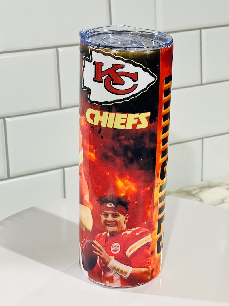 Może przedstawiać: Kubek ze stali nierdzewnej z czerwono-czarno-ż&oacute;łtym wzorem przedstawiającym logo Kansas City Chiefs i wizerunek gracza. Kubek ma przezroczystą pokrywkę.