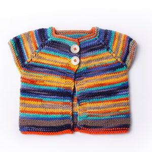 Può includere: Un cardigan di maglia a righe colorate con maniche corte e due bottoni. Il cardigan è realizzato con una varietà di colori, tra cui arancione, giallo, blu, verde e marrone.