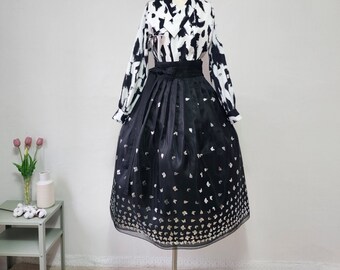 May include: A black skirt with a silver floral pattern and a white and black patterned blouse. The skirt is a traditional Korean hanbok style.
