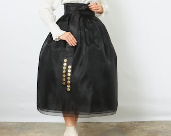 May include: A woman wearing a traditional Korean Hanbok. The outfit includes a white blouse with a V-neck and long sleeves, a high-waisted black skirt with gold embellishments, and white ankle boots. The skirt is floor-length.