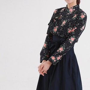May include: A navy blue blouse with a floral print and a matching navy blue skirt. The blouse has a mandarin collar and long sleeves. The skirt has a wide waistband and a pleated design.