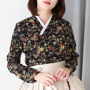 May include: A black long-sleeved blouse with a white collar and a floral print. The blouse has a V-neckline and a button closure at the cuffs.