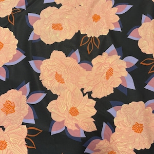 May include: A fabric featuring a repeating floral pattern on a black background. The design consists of large, light peach-colored flowers with fine line details and orange centers, interspersed with light purple and dark blue leaves and stems.