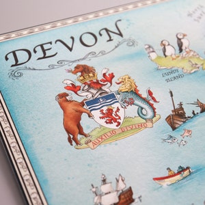 Pode incluir: Um mapa de estilo vintage de Devon, Inglaterra, com um bras&atilde;o de armas que apresenta um le&atilde;o vermelho, um touro e uma serpente marinha. O mapa &eacute; pintado em aquarela e inclui detalhes como um farol, um barco e um papagaio-do-mar.