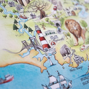 Pode incluir: Uma ilustra&ccedil;&atilde;o de aquarela de um mapa com um farol vermelho e branco, uma ponte e um rio. O mapa tamb&eacute;m apresenta um le&atilde;o, um elefante e um navio. O texto no mapa inclui "Tavistock", "Plymouth", "South Hams", "Noss Mayo", "Burgh Island" e "Hope Cove".