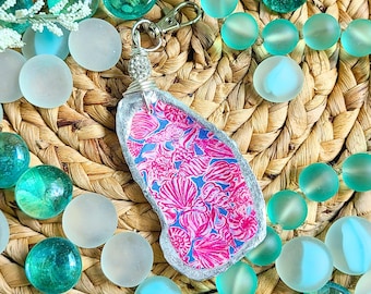 May include: A silver charm with a pink and blue patterned design, attached to a silver key chain. The charm is surrounded by turquoise and white glass beads.