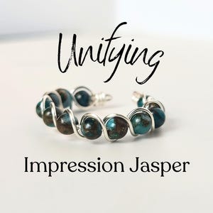 May include: A silver wire wrapped ring with turquoise and brown impression jasper beads. The ring is on a white background and the word "Unifying" is written above the ring.