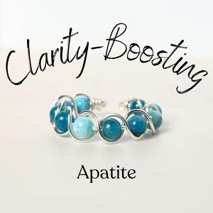 May include: Apatite bracelet with Clarity-Boosting text. The bracelet features a series of blue and turquoise beads encased in silver-colored wire. The beads vary in shade, creating a visually appealing contrast. The bracelet is displayed on a white background.