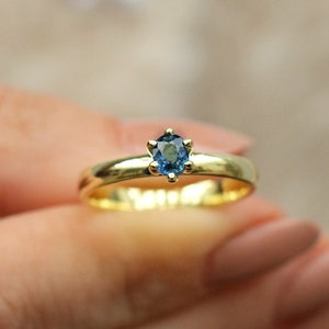 Può includere: Un anello d'oro con una pietra preziosa blu incastonata a griffe.