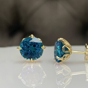 Pu&ograve; includere: Un paio di orecchini a lobo in oro con pietre preziose blu. Gli orecchini hanno un design delicato e ornato.
