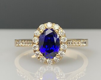 Op de afbeelding: Een gouden ring met een grote ovale blauwe saffier omringd door een halo van kleinere diamanten.