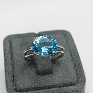 May include: A silver ring with a large oval-shaped blue topaz gemstone and smaller diamond accents.