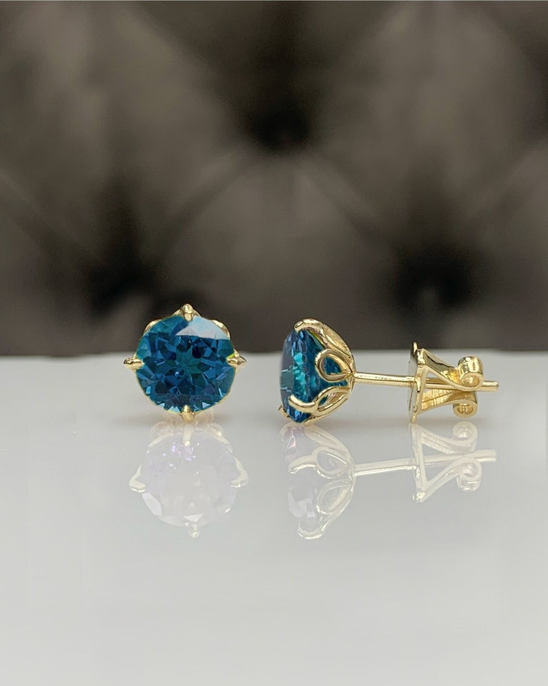 Pu&ograve; includere: Un paio di orecchini a lobo in oro con pietre preziose blu. Gli orecchini hanno un design delicato e ornato.